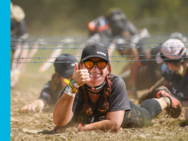 Woman lying on ground giving the thumbs up sign during the Spartan event